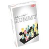 Pudełko gry logicznej z napisem "Collection Classique RUMMY" oraz logo "TACTIC" w czerwonym kolorze. Na ilustracji widoczne są pionki z cyframi i symbolami w różnych kolorach, ustawione na czarnych stojakach.