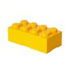 Żółte pudełko śniadaniowe w kształcie klocka z ośmioma wypustkami, na których widnieje logo "LEGO". Pudełko ma prostokątny kształt i gładką powierzchnię.