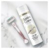 Na zdjęciu znajduje się puszka żelu do golenia z napisem "200ml Satin Care Dry Skin Olay Vanilla Scent Shave Gel" oraz różowa maszynka do golenia z wymienną głowicą, na której widnieje napis "Venus". Tło jest marmurowe.