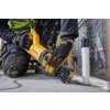Osoba ubrana w robocze rękawice trzyma żółtą piłę szablastą marki DEWALT, której ostrze jest skierowane w stronę podłogi. Na rękawicy widoczne jest logo DEWALT.