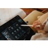 Na zdjęciu widać tablet z otwartym menedżerem plików, do którego podłączony jest pendrive. Osoba trzyma rysik nad ekranem, na którym widoczne są miniatury zdjęć i folderów.