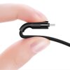 Zbliżenie na czarny kabel USB-C z zakrzywioną końcówką, trzymany pomiędzy palcami. Kabel ma plecioną osłonę, a końcówka jest metalowa.