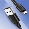Na zdjęciu widoczny jest czarny kabel USB z końcówkami USB i Micro USB, na których znajduje się napis "UGREEN". Tło jest w odcieniach niebieskiego.