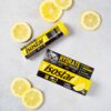 Na zdjęciu widoczne są opakowanie i tubka produktu "Isostar Hydrate & Perform Power Tabs" o smaku cytrynowym, otoczone plasterkami cytryny. Na opakowaniu znajdują się napisy: "HYDRATE & PERFORM POWER TABS", "BEFORE DURING AFTER", "LEMON FLAVOUR", "ELECTROLYTE FORMULA", "EASY TO PREPARE", "NATURAL FLAVOURING".