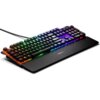 Na zdjęciu znajduje się klawiatura z podświetleniem RGB, z widocznym logo "SteelSeries" na podpórce na nadgarstki. Klawisze są podświetlone w różnych kolorach, tworząc efekt tęczy.