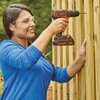 Osoba w niebieskiej bluzce używa wiertarko-wkrętarki BLACK&DECKER BDCDC18 do wiercenia w drewnianej konstrukcji. Na urządzeniu widoczne są napisy: "BLACK+DECKER" oraz "LITHIUM 18V".