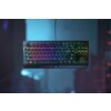 Na zdjęciu widoczna jest klawiatura z podświetleniem RGB, zawieszona w powietrzu na tle rozmytego, niebiesko-fioletowego tła. Na obudowie klawiatury znajduje się logo producenta.