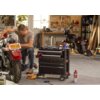 Na zdjęciu znajduje się warsztat z motocyklem, przy którym pracuje mężczyzna, oraz czarny regał z szufladami KETER Tool Chest 237791, na którym leżą narzędzia. W tle widoczne są półki z narzędziami i materiałami oraz drugi motocykl.