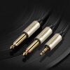 Na zdjęciu widoczne są trzy kable audio z metalowymi wtykami, z których dwa to Jack 6.35 mm, a jeden to TRS 3.5 mm, wszystkie oznaczone logo "UGREEN". Kable mają plecioną osłonę i złote końcówki, a tło jest ciemne i teksturowane.