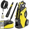 Zdjęcie przedstawia myjkę ciśnieniową KARCHER K7 Smart Control Home 1.317-203.0 wraz z akcesoriami, takimi jak wąż, lanca, butelka z detergentem oraz urządzenie do czyszczenia powierzchni. Na myjce widoczne są napisy "KARCHER" i "K7 SMART CONTROL".