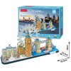 Na zdjęciu znajduje się zestaw puzzli 3D przedstawiający londyńskie zabytki, takie jak Big Ben, London Eye i Tower Bridge, z opakowaniem w tle. Na pudełku widnieje napis "CubicFun CityLine London 3D Puzzle 107 Pieces" oraz grafika nocnej panoramy Londynu.