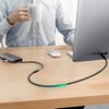 Na zdjęciu widać biurko, na którym znajduje się komputer, myszka oraz hub USB z podłączonym kablem USB-C. Kabel jest podłączony do komputera, a na hubie widnieje logo "UGREEN".