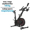 Na zdjęciu znajduje się czarny rower spinningowy z czerwonymi akcentami, z widocznym napisem "RACER" na obudowie. Obok roweru widnieje tekst: "max. waga użytkownika 130 kg, rodzaj oporu magnetyczny".