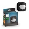 Pudełko z czujnikiem ruchu marki Philips Hue, na którym widnieje napis "PHILIPS hue personal wireless lighting Accessories Outdoor Outdoor sensor". Obok pudełka znajduje się sam czujnik w kolorze czarnym z białą, półkulistą powierzchnią.
