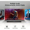 Na zdjęciu widoczny jest czarny soundbar z wyświetlaczem, umieszczony przed telewizorem, na którym widać gitarzystę na scenie. Nad telewizorem znajduje się tekst: "Multiple Audio Enhancements, Switch Freely", a poniżej są ikony z napisami: "Movie Mode", "