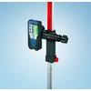 Odbiornik laserowy BOSCH LR 1G 1608M0070F zamocowany na statywie z podziałką liczbową, z widocznym logo BOSCH na urządzeniu i uchwycie. Tło jest jednolite, w jasnym odcieniu niebieskiego.