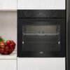 Czarny piekarnik elektryczny w zabudowie z wyświetlaczem cyfrowym pokazującym "00:34" oraz pokrętłami do ustawiania funkcji i temperatury. Na blacie obok piekarnika stoi miska z czerwonymi jabłkami.