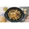 Na zdjęciu znajduje się multicooker z pieczonym kurczakiem na ziemniakach, obok leży chleb, butelka z oliwą oraz dwa widelce na serwetce w kratkę. Produkt to "Multicooker CECOTEC 2031".