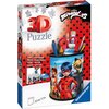 Opakowanie produktu przedstawia kolorowy przybornik z postaciami z serii "Miraculous", wykonany z puzzli 3D. Na opakowaniu widnieje napis "3D Puzzle" oraz "Ravensburger", a także informacje o stabilności bez użycia kleju w kilku językach.