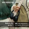Na zdjęciu widoczne są czarne słuchawki nauszne zawieszone na ramieniu osoby, która trzyma torbę. Na zdjęciu znajduje się tekst: "WH-1000X M5", "Bateria 30 godz.*", "3 min ładowania = 3 godz. odtwarzania", oraz drobny tekst: "*z włączoną funkcją redukcji 