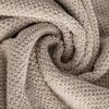 Zbliżenie na beżowy ręcznik o fakturze frotte, zwinięty w spiralę. Materiał ma widoczną, miękką strukturę z pętelkami.