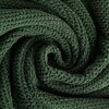 Zdjęcie przedstawia zbliżenie na teksturę ręcznika w kolorze butelkowej zieleni, ułożonego w spiralny wzór. Materiał ma wyraźną, miękką strukturę z widocznymi splotami włókien.
