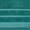 Turkusowy ręcznik z widocznymi poziomymi pasami ozdobionymi białym wzorem geometrycznym. Materiał ma teksturę frotte, a wzór składa się z powtarzających się kształtów przypominających małe kielichy.