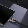 Na zdjęciu widać czarny kabel USB - Lightning podłączony do urządzenia, z metalicznym wykończeniem wtyczki i plecionym przewodem. W tle znajduje się ciemna, gładka powierzchnia.