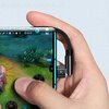 Na zdjęciu widać dłoń trzymającą smartfon z podłączonym kablem USB-C, który ma czarny, pleciony przewód. Na ekranie telefonu wyświetlana jest gra z widocznymi elementami interfejsu, takimi jak licznik FPS, czas gry "00:32" i liczba "56".