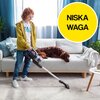 Na zdjęciu widać osobę używającą odkurzacza w salonie, gdzie na kanapie leży pies. W prawym górnym rogu znajduje się żółte koło z napisem "NISKA WAGA".