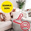 Na zdjęciu znajduje się jasna sofa z kilkoma ozdobnymi poduszkami i kocem, obok której widoczna jest roślina doniczkowa oraz regał z książkami. W lewym górnym rogu znajduje się żółte koło z czarnym napisem "SSAWKA SOFA" oraz czerwony zarys ssawki i ikona 