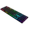 Na zdjęciu widoczna jest klawiatura z podświetleniem RGB, które emituje różnokolorowe światło pod klawiszami. Klawiatura ma smukły design i posiada pełny układ klawiszy, w tym klawiaturę numeryczną oraz rolkę do regulacji głośności.