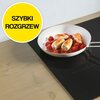 Na zdjęciu znajduje się płyta indukcyjna z białą patelnią, na której smażone są potrawy. W lewym górnym rogu widoczny jest żółty okrąg z czarnym napisem "SZYBKI ROZGRZEW".
