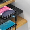 Na zdjęciu widoczne są dwa telefony leżące na półkach, do których podłączone są magnetyczne kable USB. Kable mają czarne obudowy, a jeden z nich emituje niebieskie światło.