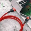 Czerwony kabel USB - Micro USB USAMS U26 2A 1 m jest podłączony do laptopa i smartfona, leżących na szarej powierzchni. Na kablu widoczne jest logo "USAMS", a obok napis "RED".