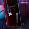 Na zdjęciu znajduje się biały kabel USB - Micro USB o długości 1 metra, marki USAMS U38, podłączony do telefonu z widocznym napisem "micro USB". Kabel jest przedstawiony na tle ciemnego, kolorowego telefonu.