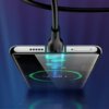 Na zdjęciu widoczny jest czarny kabel USB-C podłączony do smartfona, na którego ekranie wyświetla się zielony okrąg z napisem "80%". Kabel emituje niebieskie światło w miejscu połączenia z urządzeniem.