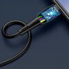 Czarny kabel USB-C z widocznym wnętrzem wtyczki, ukazującym kolorowe przewody i niebieską płytkę drukowaną, jest podłączony do urządzenia elektronicznego. Kabel jest lekko zwinięty na ciemnym tle.