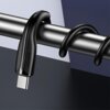 Czarny kabel USB-C marki USAMS owinięty wokół metalowego pręta, z widocznym złączem USB-C. Na obudowie kabla znajduje się napis "USAMS".