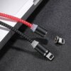 Na zdjęciu widoczny jest czerwony kabel magnetyczny USB-Lightning z czarną końcówką oraz odłączonym adapterem, leżący na ciemnej powierzchni obok urządzenia elektronicznego. Obok znajduje się również czarny kabel z podobną końcówką.