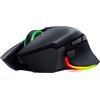 Czarna mysz komputerowa z podświetleniem RGB w kolorach tęczy, widoczna od spodu z wyraźnymi elementami konstrukcyjnymi i oznaczeniami, takimi jak "RAZER BASILISK PRO" oraz symbolem CE. Obok myszy znajdują się dwa odłączone elementy, w tym jeden z napisem