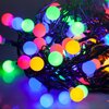 Kolorowe lampki choinkowe LED w kształcie kul, splecione w gęstą wiązkę, emitują światło w odcieniach zielonym, niebieskim, czerwonym, różowym i żółtym. Przewody są ciemne i widoczne między kulami.