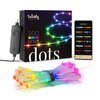 Na zdjęciu znajduje się opakowanie lampek choinkowych z napisem "twinkly generation II", "200 multicolor", "app controlled RGB LED" oraz "dots". Obok opakowania widoczny jest kontroler, smartfon z aplikacją oraz zwinięty sznur kolorowych lampek LED.