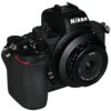 Aparat fotograficzny z widocznym obiektywem, na którym znajduje się napis "LAOWA 10mm f/4.0 Cookie Ø37mm". Na korpusie aparatu widoczny jest napis "Nikon".