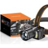 Na zdjęciu znajduje się latarka czołowa z dużym obiektywem, umieszczona obok pudełka z napisem "SUPERFIRE" oraz "HEADLAMP". Na opasce latarki widoczny jest napis "SUPERFIRE".