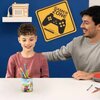 Na zdjęciu znajduje się kolorowy przybornik z motywem Super Mario, wypełniony kolorowymi ołówkami, umieszczony na białym stole. W tle widoczny jest żółty znak z napisem "GAMER ZONE" oraz półka z dekoracyjnym radiem.