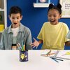 Na zdjęciu znajduje się przybornik z motywem Pikachu, wypełniony kolorowymi kredkami, umieszczony na białym stole. W tle widoczne są niebieska ściana, półka z dekoracjami oraz fragmenty zeszytów i przyborów szkolnych.