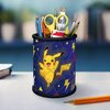 Na zdjęciu znajduje się przybornik w kształcie walca z motywem Pikachu na niebieskim tle, ozdobiony żółtymi błyskawicami i trójkątami. W przyborniku umieszczone są różne przybory, takie jak nożyczki, pędzle, ołówki i długopisy.