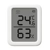 Na zdjęciu widoczny jest biały termometr z wyświetlaczem cyfrowym, na którym pokazana jest temperatura 24,6°C oraz wilgotność 63%. Na górze ekranu znajduje się ikona uśmiechu z napisem "COMFORT" oraz wskaźnik poziomu baterii.