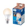 Na zdjęciu widoczna jest inteligentna żarówka LED oraz jej opakowanie. Na opakowaniu znajdują się napisy: "PHILIPS", "Smart LED", "Easy control with app or voice", "13W = 100W", "1521 lumen", "E27", oraz ikony Wi-Fi i Bluetooth.